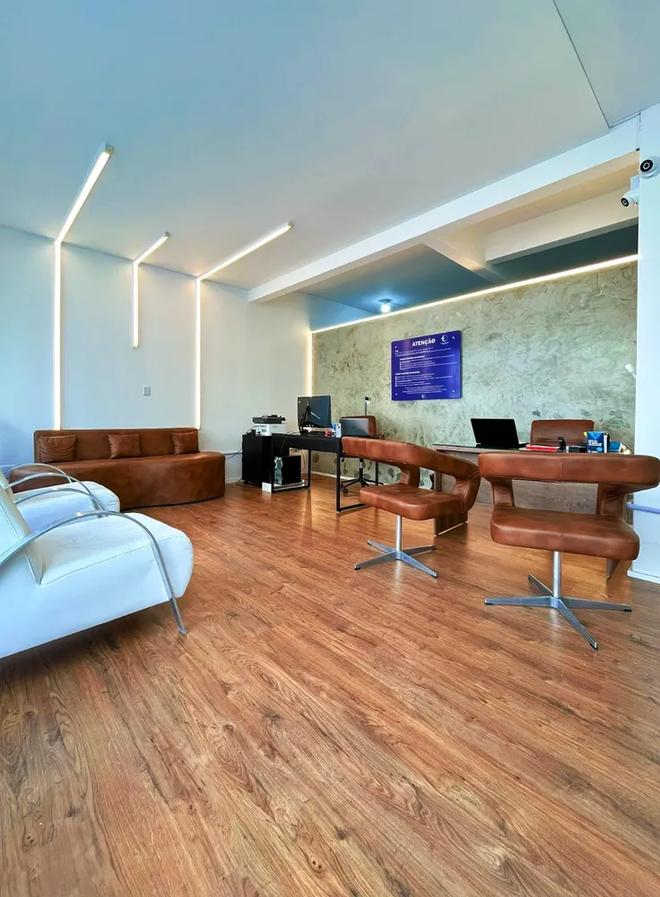 Recepção com sofá e poltronas de couro e piso de madeira